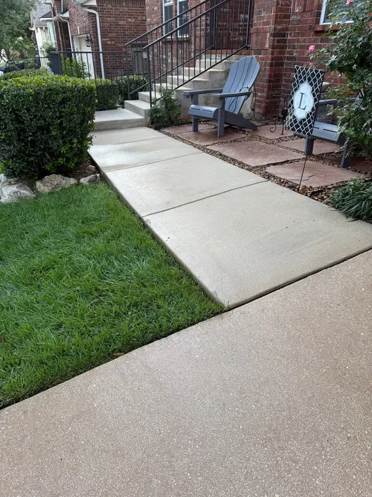 The Service Displayed Is Pressure Washing Of Concrete Surfaces And Cleaning Of Surrounding Landscaping Elements